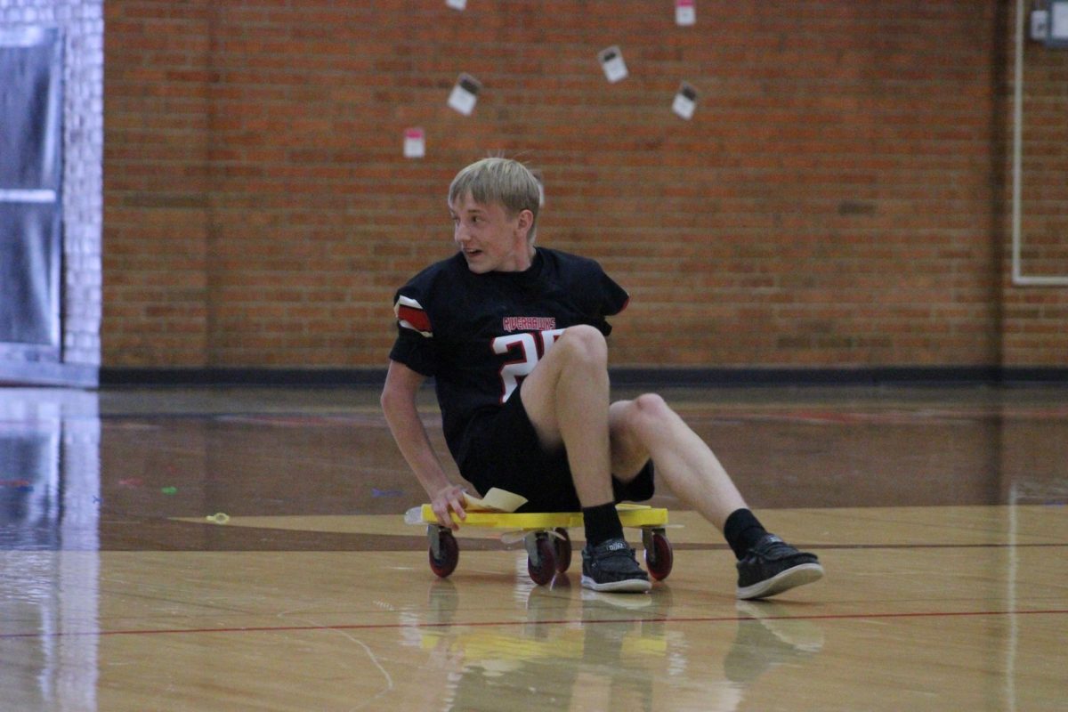 Sophomore Carter Long takes off on a scooter trying to win a race across the gym for his class.