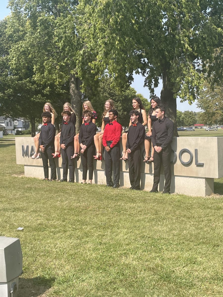 The court poses for a photo in front of the Mason City High School sign. From left to right Savannah Davis, Javel Lee, Maggie Berding, Noah Honn, Janae Hansen, Gaige Younke, Miah Anderson, Jonathan Thangaraj, Celia Flores,  Saul Morales, Joseline Juarez, and Brandt Haakenstad. 