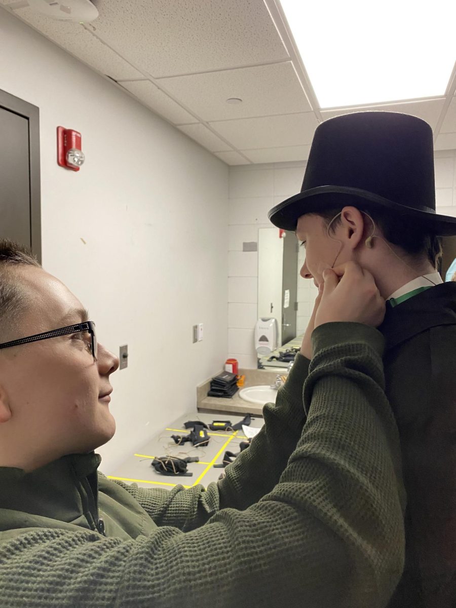 Jamie Tinajero helps Timothy Dietrich II put on his microphone before Dietrich's performance of the song Stars, from the musical Les Miserables. 