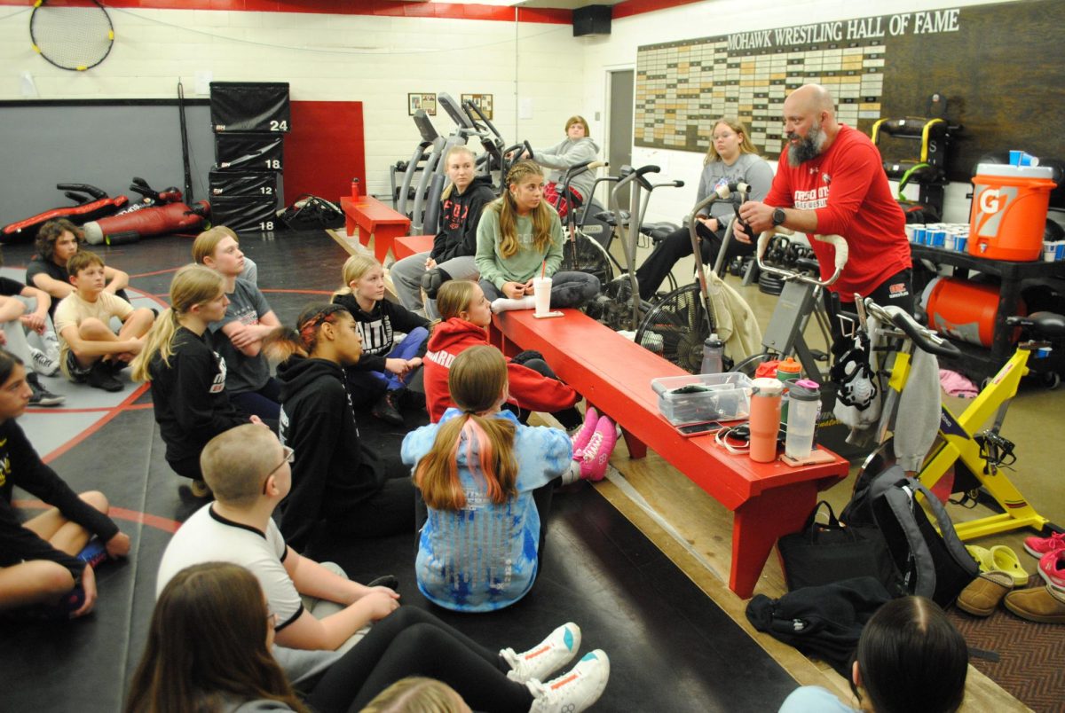 Coach Jake Phillips meets with his wrestlers in a huddle at the beginning of practice in January. The Iowa Wrestling Coaches and Officials Assocation recently selected him 2A Coach of the Year. 