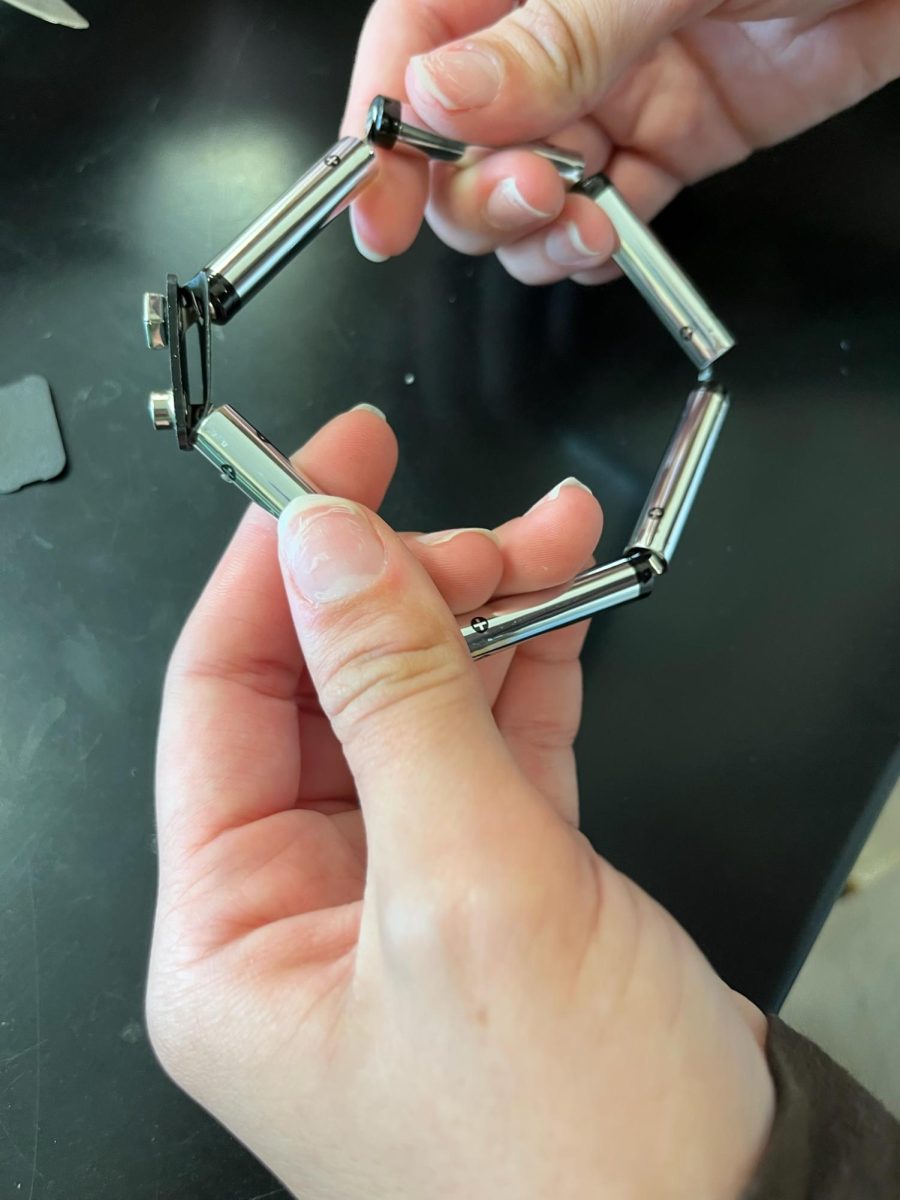 A student reveals the way the six internal cells are connected by a wire through their centers. 