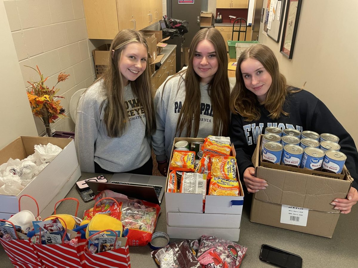 In the commons after school, Addyson Nepple, Madelyne Stankey, and Kayla Eide represent the Key Club in their food drive for Hawkeye Harvest Food Bank. 