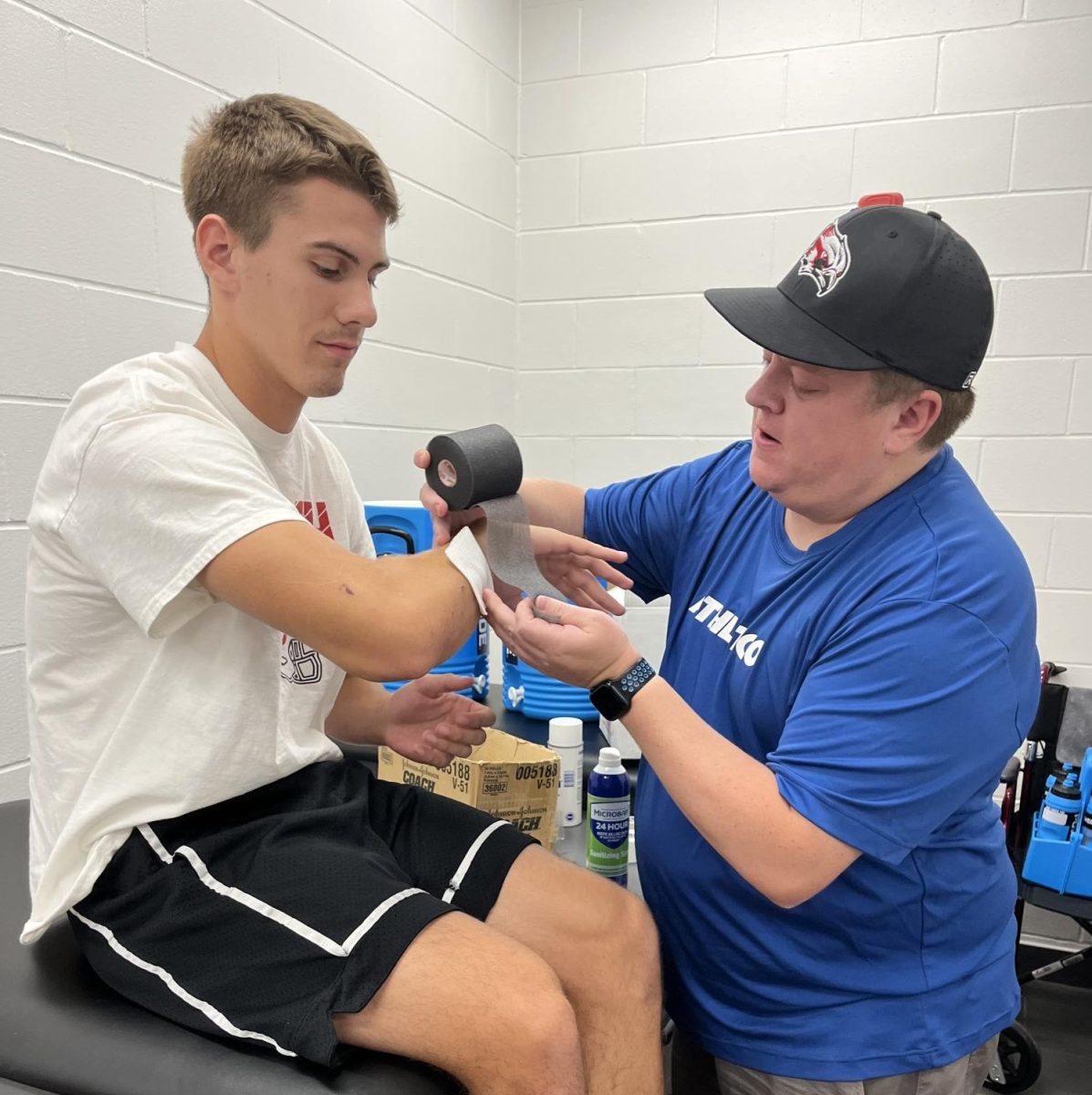 Athletic trainer John Knapper tapes up senior Dane Hanson’s wrist for football practice.